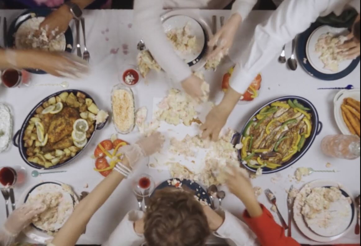 Film still: hands tearing into the cake across the table