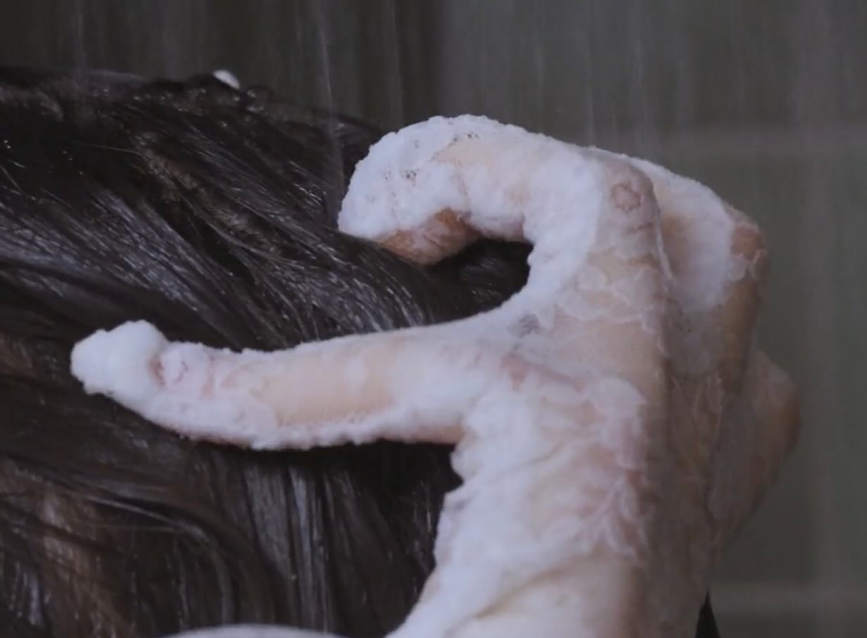 Film still: icing piped over hair in extreme close-up