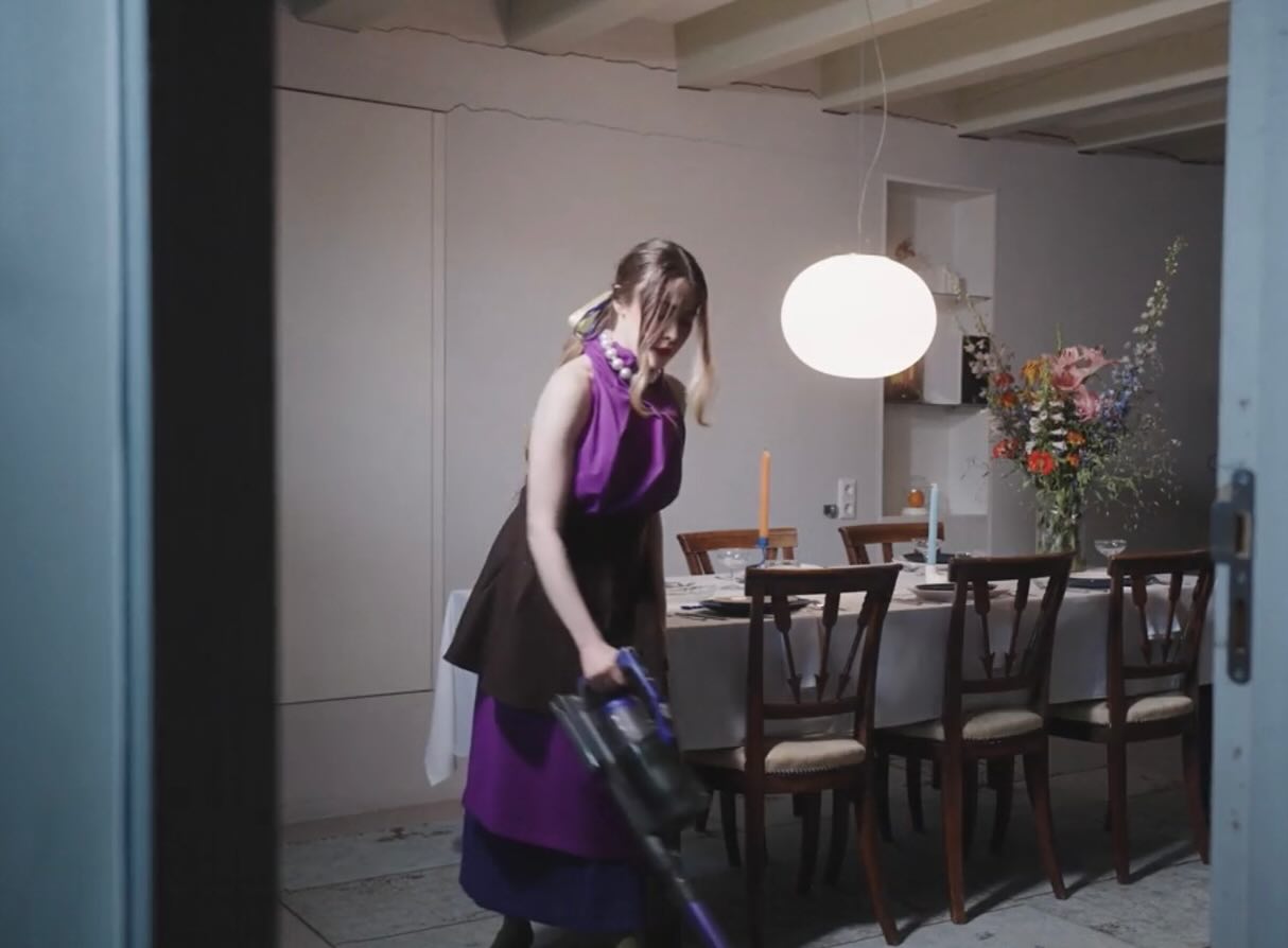 Film still: Dalia vacuuming the perfectly staged dining room